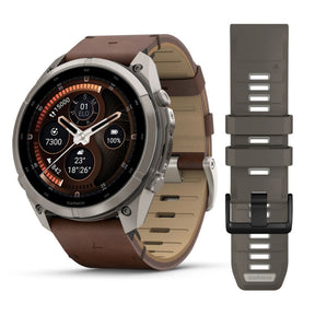 Garmin älykello harmaalla titaanikehyksellä, pyöreällä AMOLED-näytöllä ja pähkinänruskealla nahkarannekkeella sekä varahihnalla
