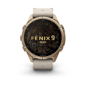 Garmin Fenix 9 Pro -älykello lämmin kullan sävyisellä titaanikotelolla, harmaalla rannekkeella ja mustalla Fenix 9 -näytöllä