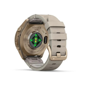 Garmin Fenix 9 älykellon takanäkymä, lämmin kullanvärinen titaanikuori, harmaa ranneke ja vihreänä hohtava sykemittari