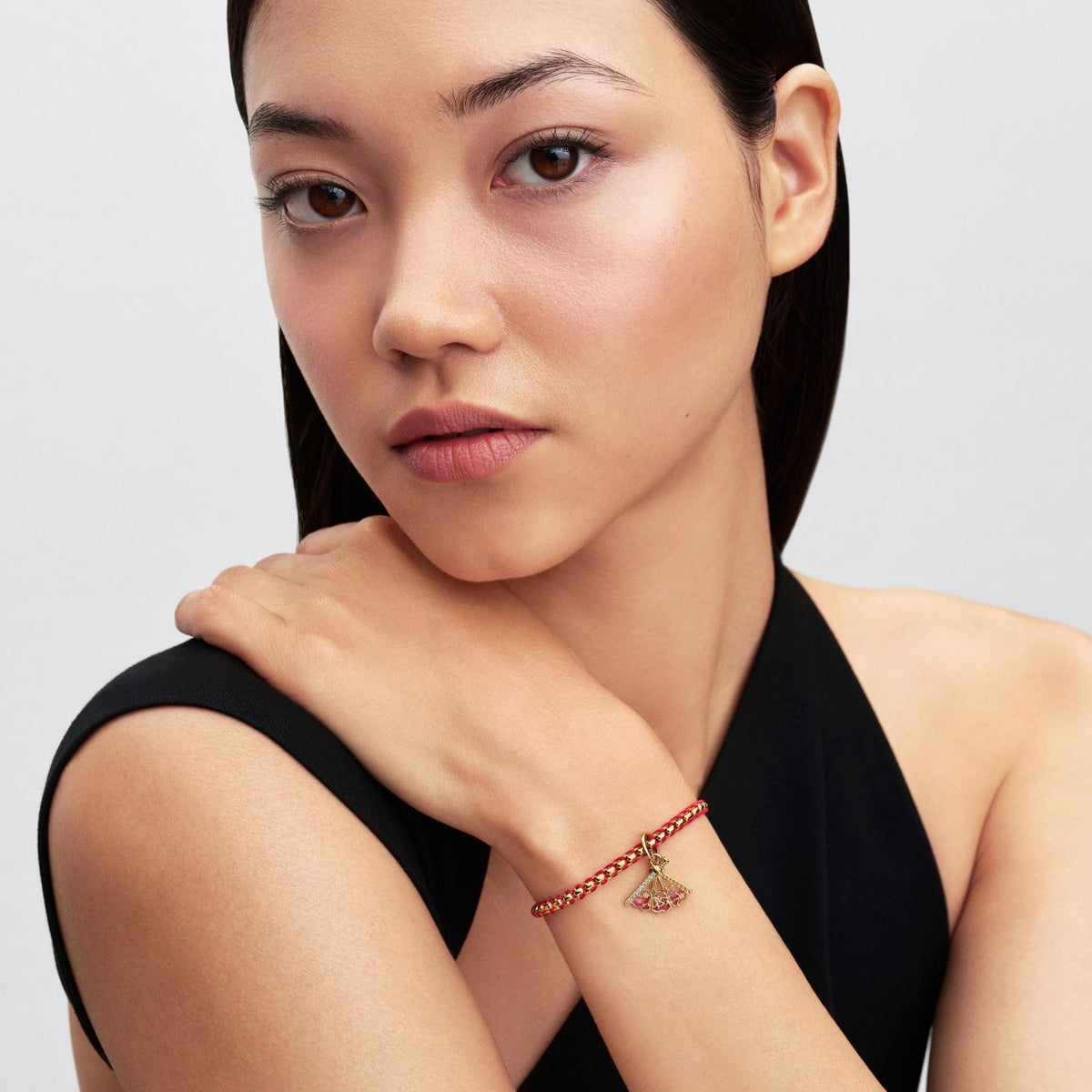 Pandora Disney Mulan -aiheinen keltakullattu danglehela punakultaisessa rannekorussa naisen ranteessa