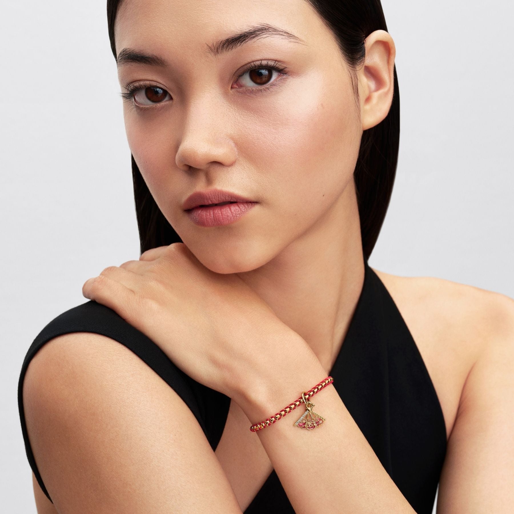 Pandora Disney Mulan -aiheinen keltakullattu danglehela punakultaisessa rannekorussa naisen ranteessa