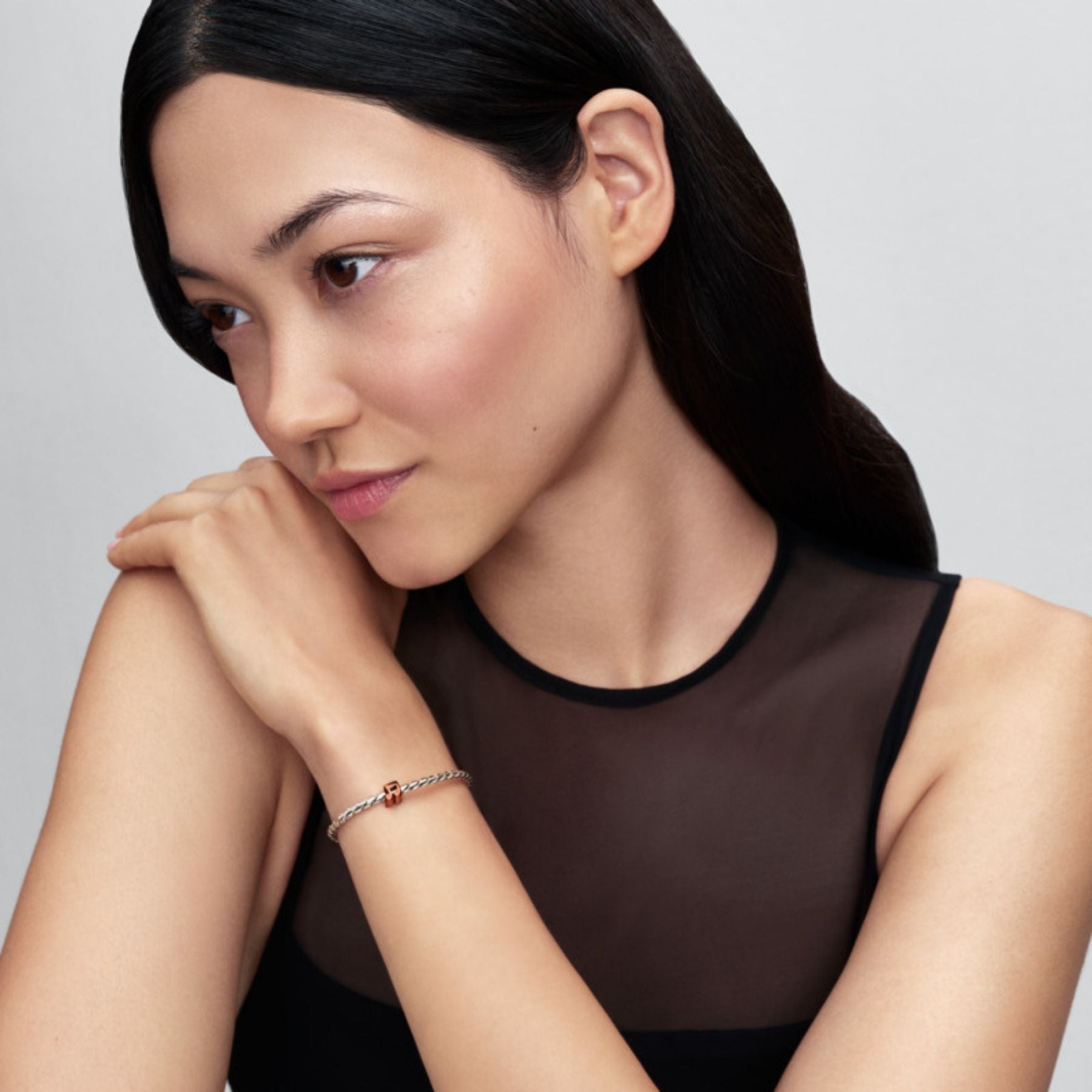 Pandora Moments hopeinen rannekoru oranssilla nuottihelalla naisen ranteessa minimalistisessa tyylissä