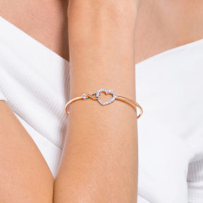 Swarovski rosekultainen kristallirannekoru, jossa säihkyvä infinity-symboli ja sydänrannekoru ranteessa