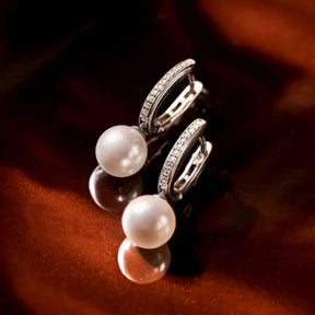 Ti Sento hopeiset rengaskorvakorut, valkoiset helmet ja säihkyvät zirkonit tummalla heijastavalla alustalla